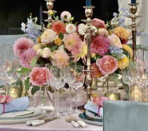 A pink and blue table setting with candles and flowers.
